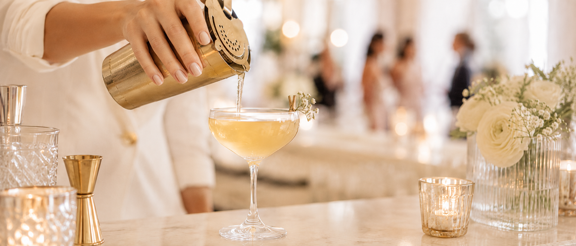 Bartender pouring a signature cocktail into a coupe at an elegant event bar
